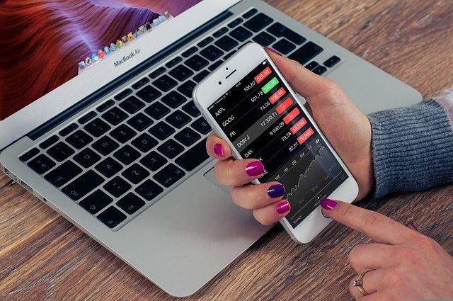 Business and IT woman holding phone showing data and laptop